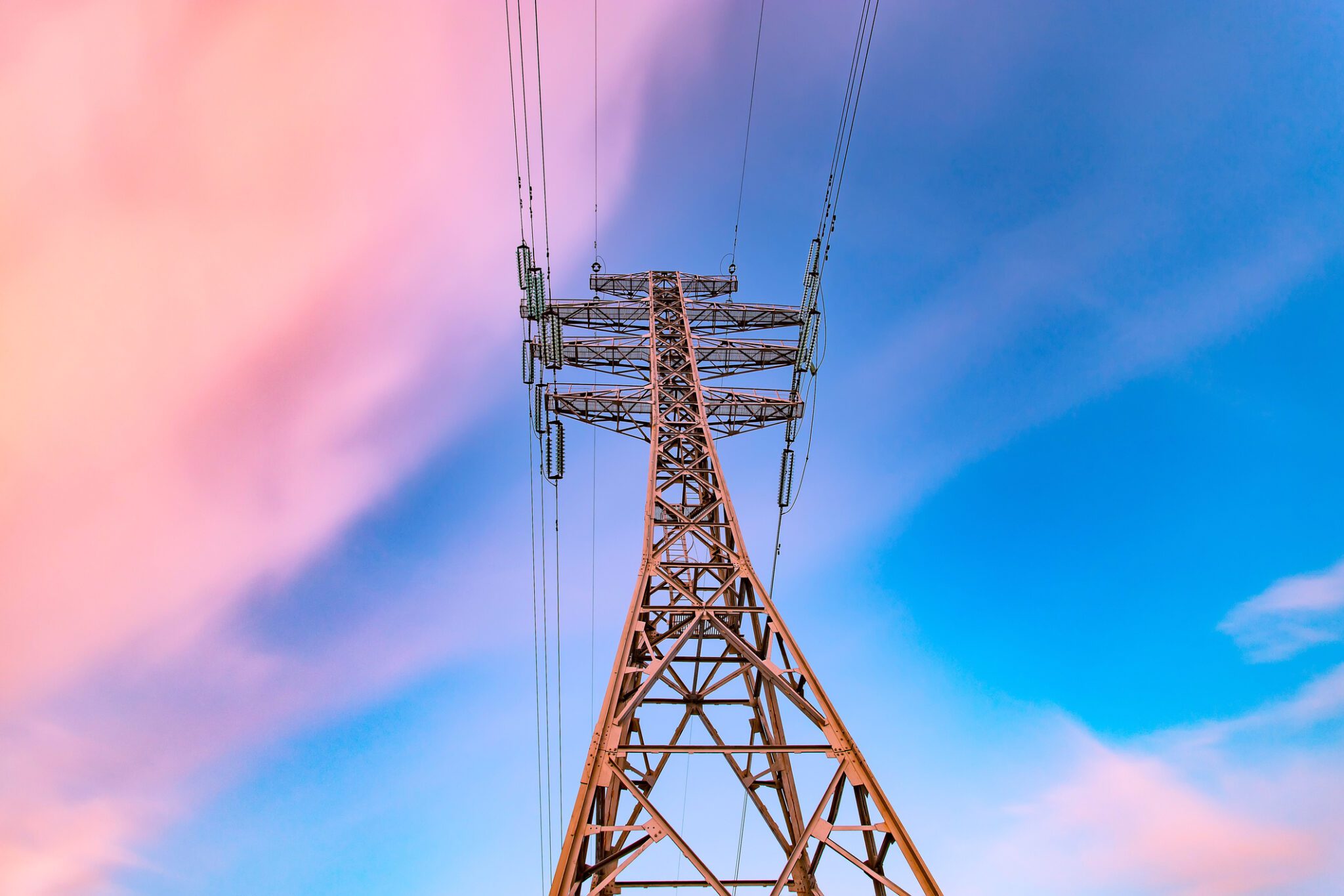 High voltage electricity pylons and transmission power lines on the blue sky background at sunset