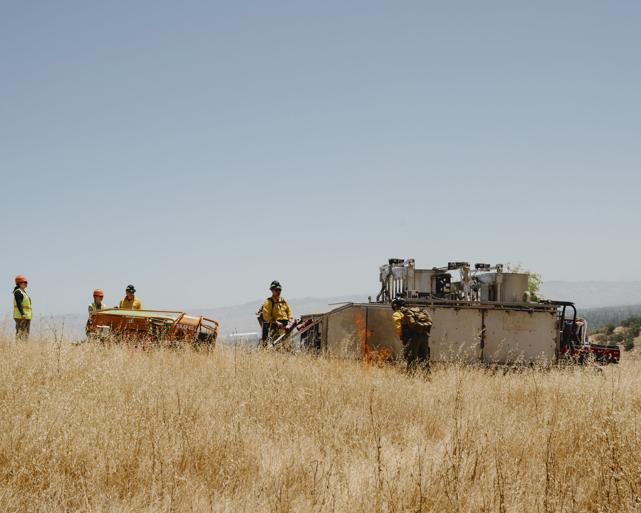 Flames escape during a test run of a Burnbot, which has been described as a giant, upside-down propane grill that facilitates controlled burns, on grasslands at Stanford University in Palo Alto, Calif., June 27, 2024. (Ian C. Bates/The New York Times)