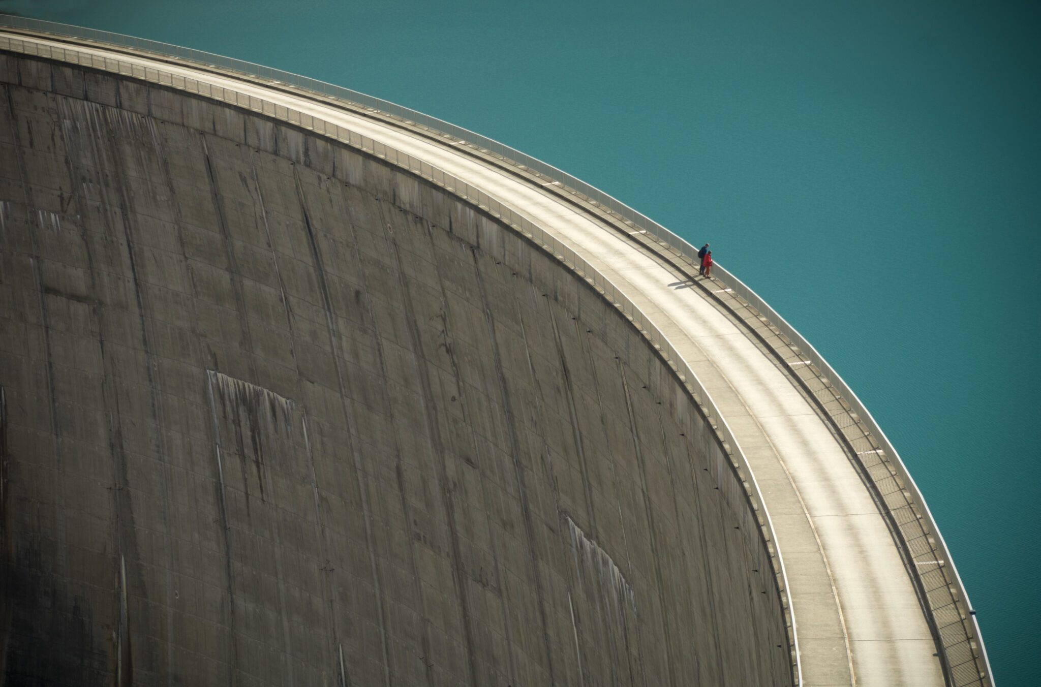 Two People Looking Over the Edge of a Large Dam